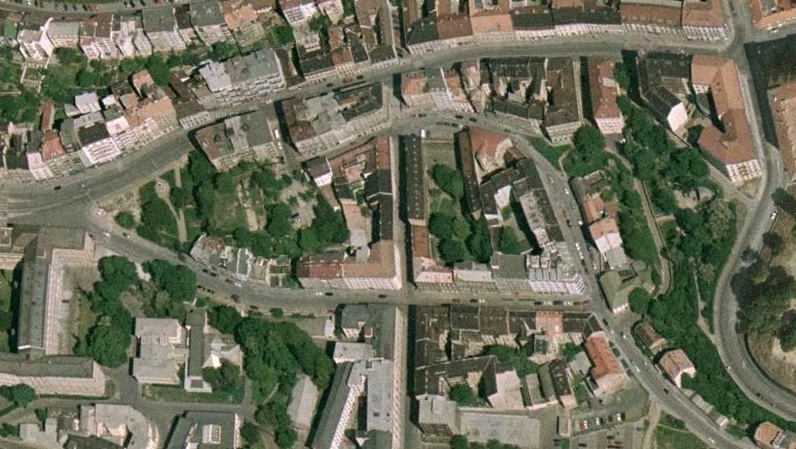 Pohled na ulice Pekařskou (vodorovně v horní části snímku), Leitnerovu (svislá osa snímku), Anenskou (vodorovná uprostřed) a mezi nimi stočenou Kopečnou ulici, která se rozvinula po úbočí kopce Puhlíku pod Petrovem možná dokonce dřív než vzniklo hradbami spoutané Brno. Areál domu U sedmi švábů se nachází vpravo od středu snímku - dva zhruba rovnoběžné domy s tmavou střechou, jeden dům s červenou střechou a skupiny stromů mezi nimi.